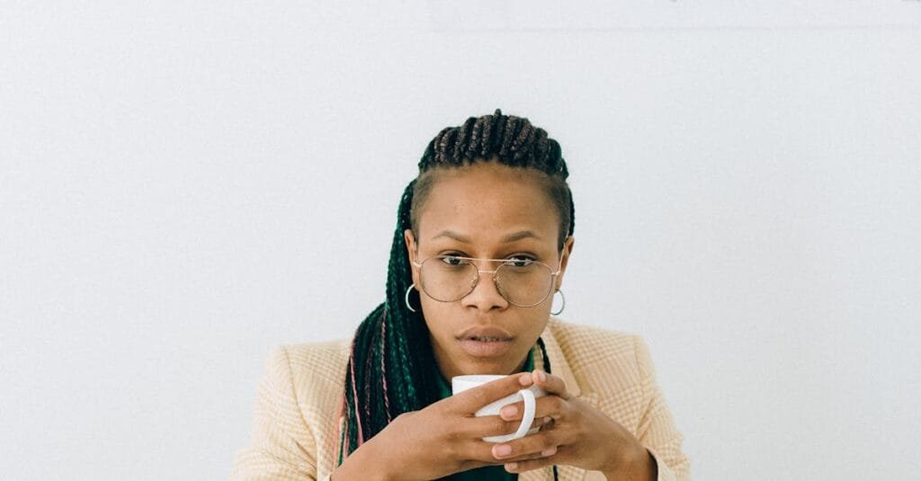 Focused businesswoman holding cup, analyzing financial data at desk.